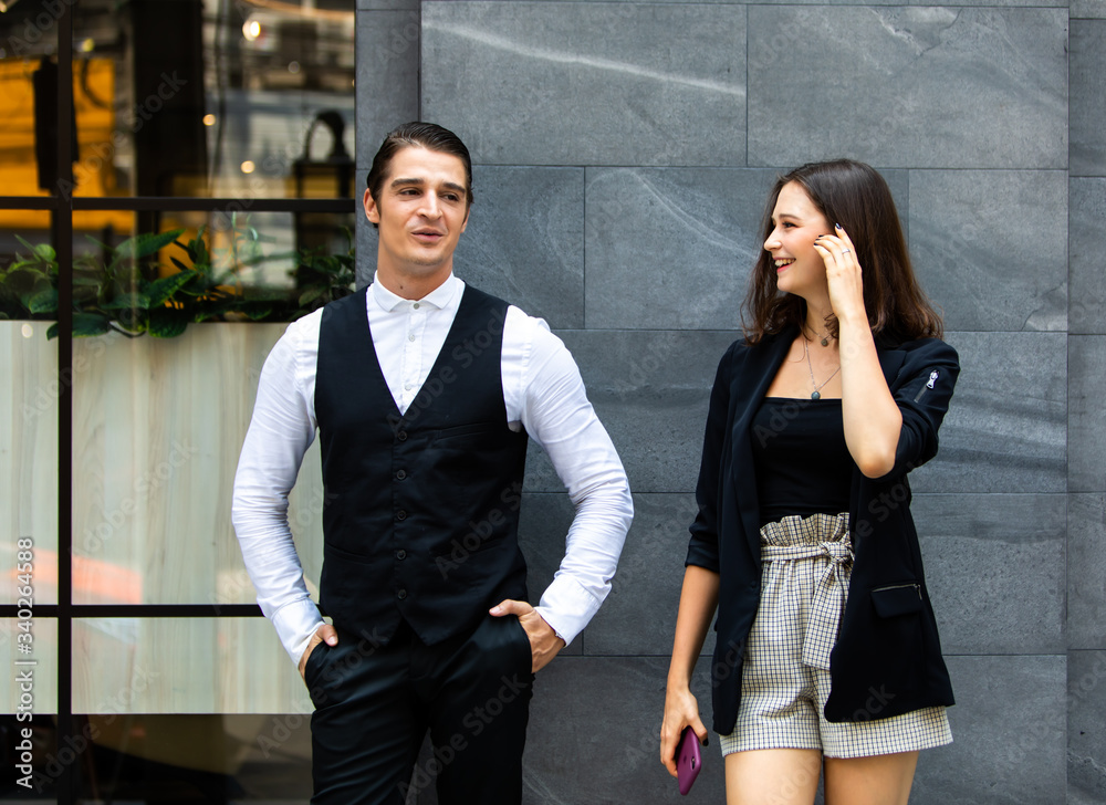 Business colleagues couple walking on street while talking to each other. Young happy business couple walking outdoor office building Business colleagues couple walking on street while talking to each other. Young happy business couple walking outdoor office building