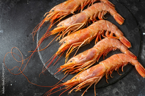 Large langoustines on a black plate on the black kitchen table. Seafood for a healthy diet