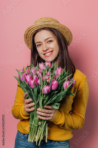Young woman with bouquet of tulips on color background