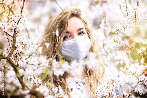 
girl in white medical mask and spring blossom