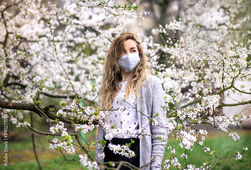 
girl in white medical mask and spring blossom