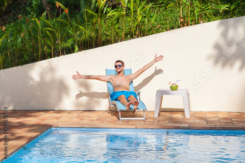 Fotografija Happy man relaxing on sunbed close to swimming pool.