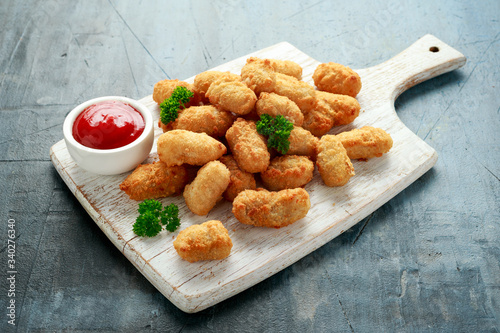 Crispy Battered scampi nuggets with ketchup on white wooden board photo