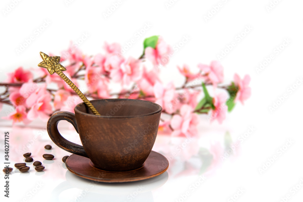 coffee Cup with a spoon, scattered coffee beans on a background of cherry blossoms on a white background coffee Cup with a spoon, scattered coffee beans on a background of cherry blossoms on a white background