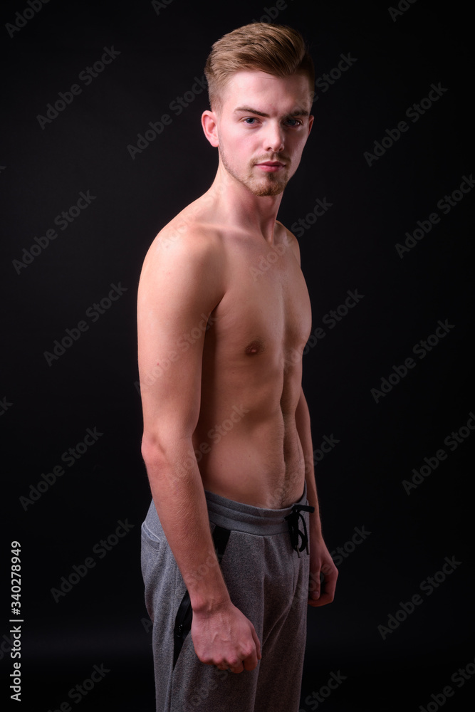 Fototapeta premium Young handsome man shirtless against black background