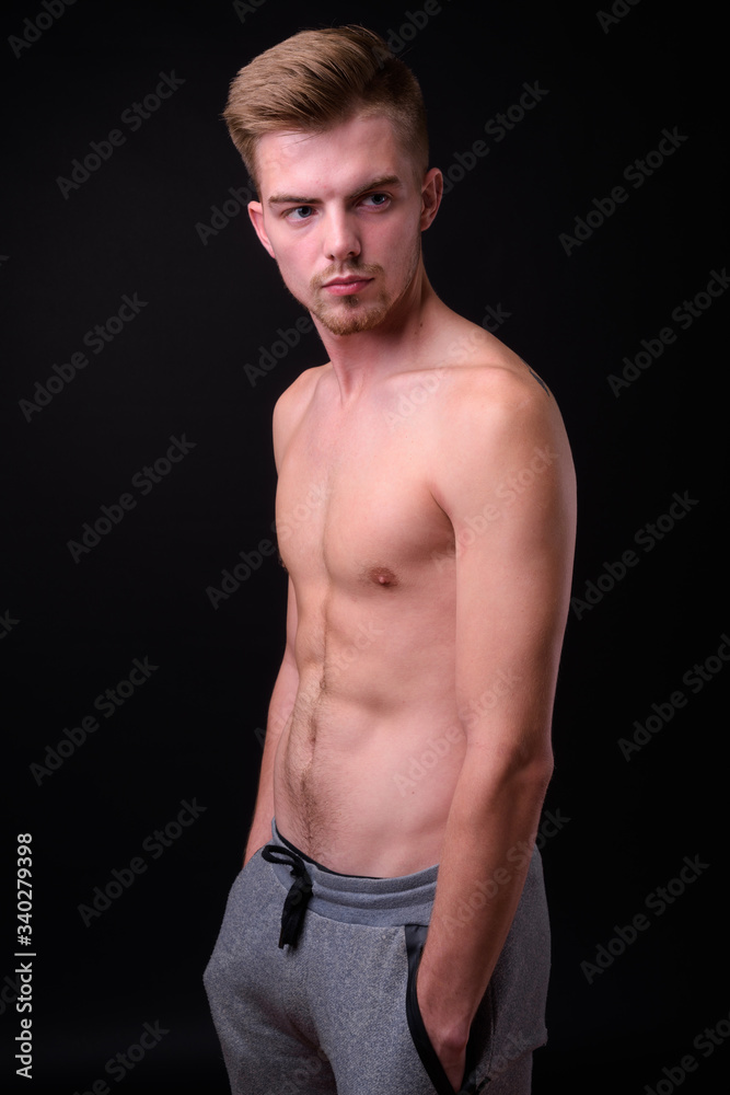 Fototapeta premium Young handsome man shirtless against black background