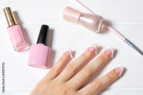 A woman glues stickers on her nails for French manicure. The girl applies nail Polish. Nail care. Nail salon, procedure, SPA. Home nail care. Manicure tools. Beauty, lifestyle, Glamour.