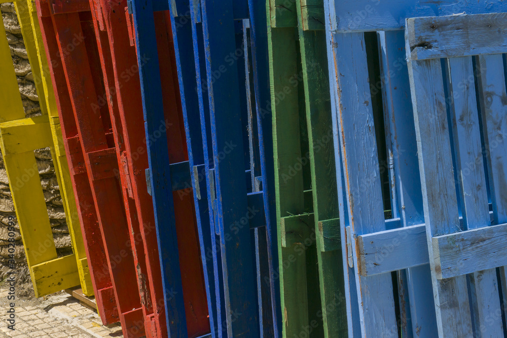 Row of wooden empty pallets painted in different colors, red, green, blue and yellow. 