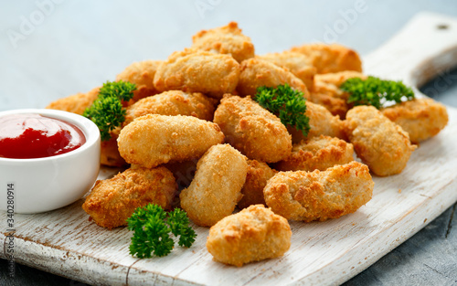 Crispy Battered scampi nuggets with ketchup on white wooden board photo