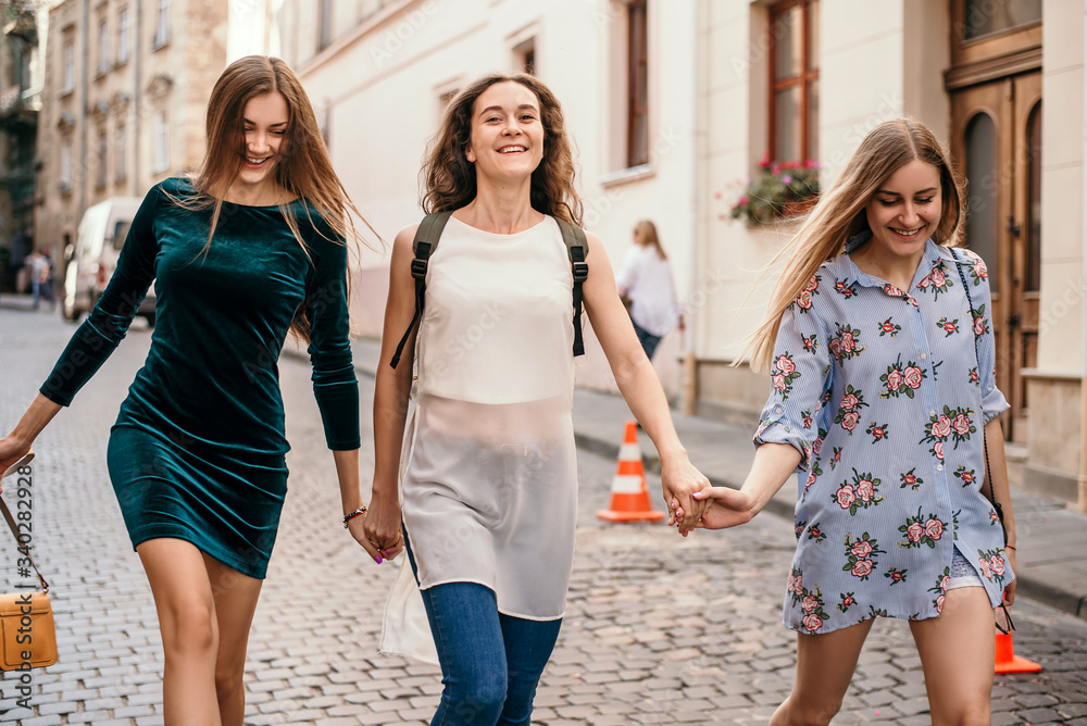 Three young women are walking in the city and having fun. Summer mood Three young women are walking in the city and having fun. Summer mood