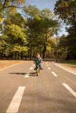 Small child driving bicycle at road for pedestrians and bicycles, bike lane in the park in fall season.