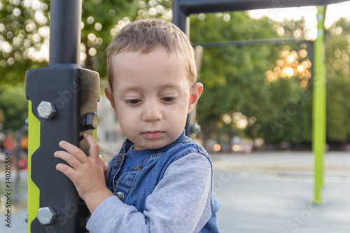 Sad small boy staying near brachiating bar at a school yard. Selective focus. photo