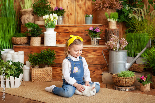 Little girl with white rabbit. Child playing with pet bunny. Kids play with animals. Child at Easter egg hunt. Cute little girl with white bunny in garden. Kid take care of pet. Spring Easter garden. 