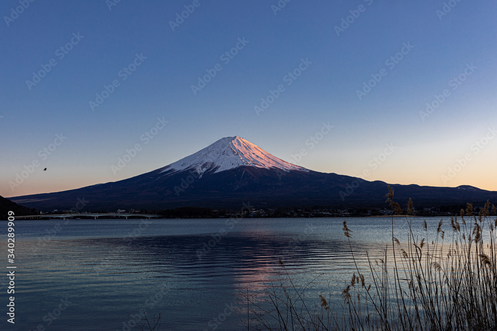 湖面に映り込む夕日に照らされた富士山