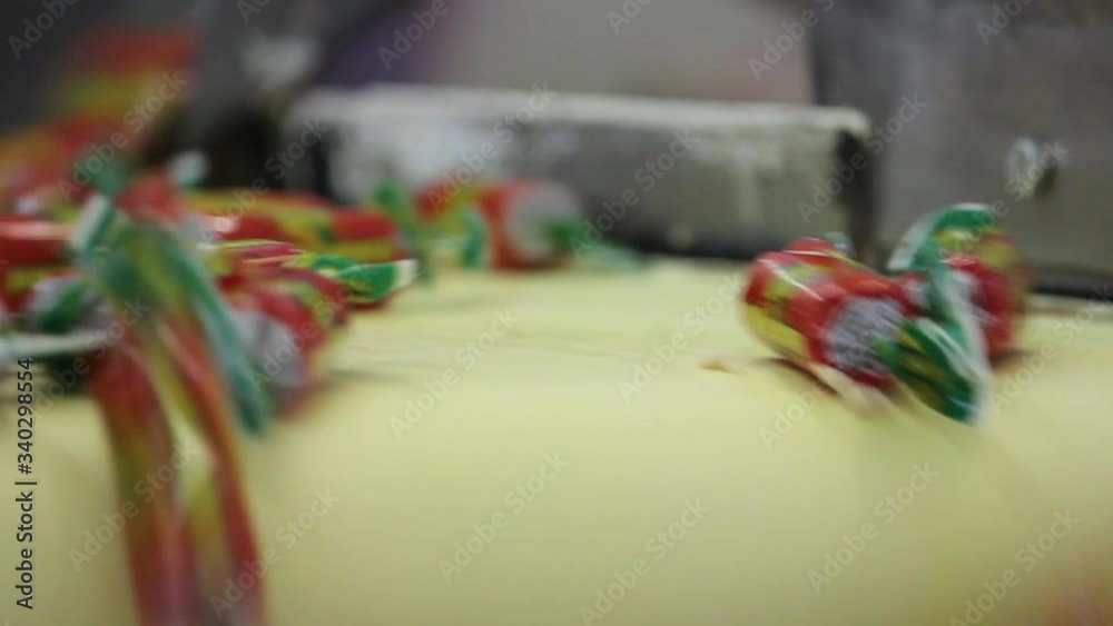 Wrapped in wrappers, the candy moves along the conveyor belt and falls. The video was shot in close-up.