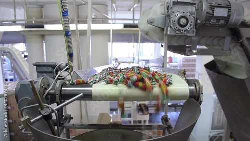 Wrapped in wrappers, the candy is delivered via a conveyor belt to the packaging machine. Vertical panorama.