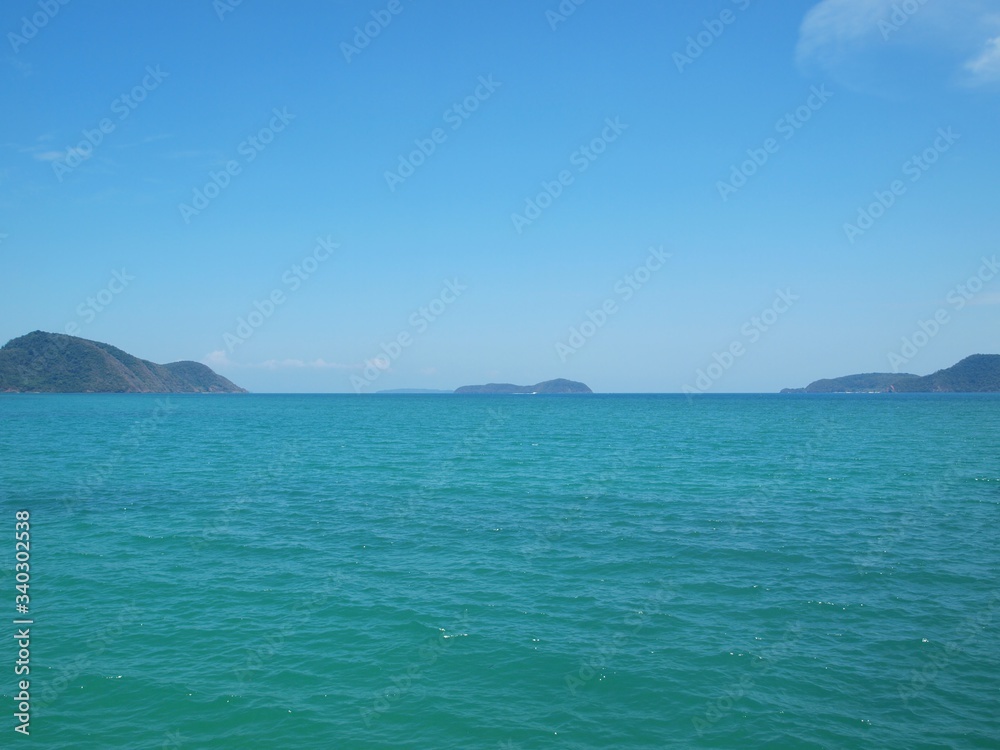 The endless expanse of the sea that goes beyond the horizon. Stunning panoramic view of the azure water and the group of small islands in the distance. Seascape. Open ocean space. Blue clear sky.