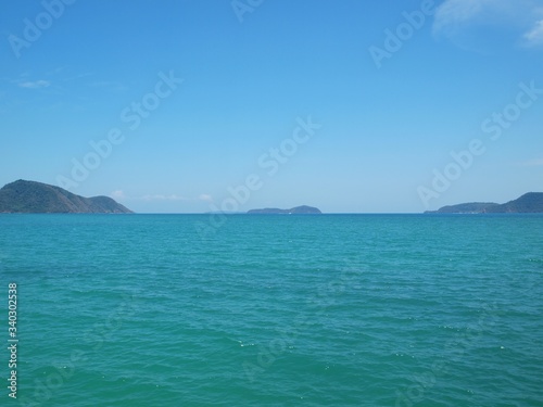 The endless expanse of the sea that goes beyond the horizon. Stunning panoramic view of the azure water and the group of small islands in the distance. Seascape. Open ocean space. Blue clear sky.