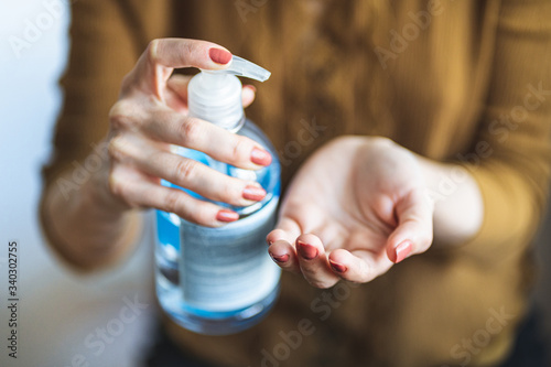 Close up female hands using wash hand sanitizer gel pump dispenser during coronavirus epidemic outbreak. Hand desinfection concept