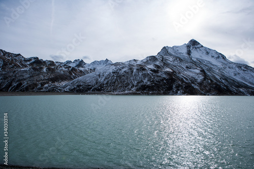 Water of a mountain lake with snowy hilltops in the background during dawn