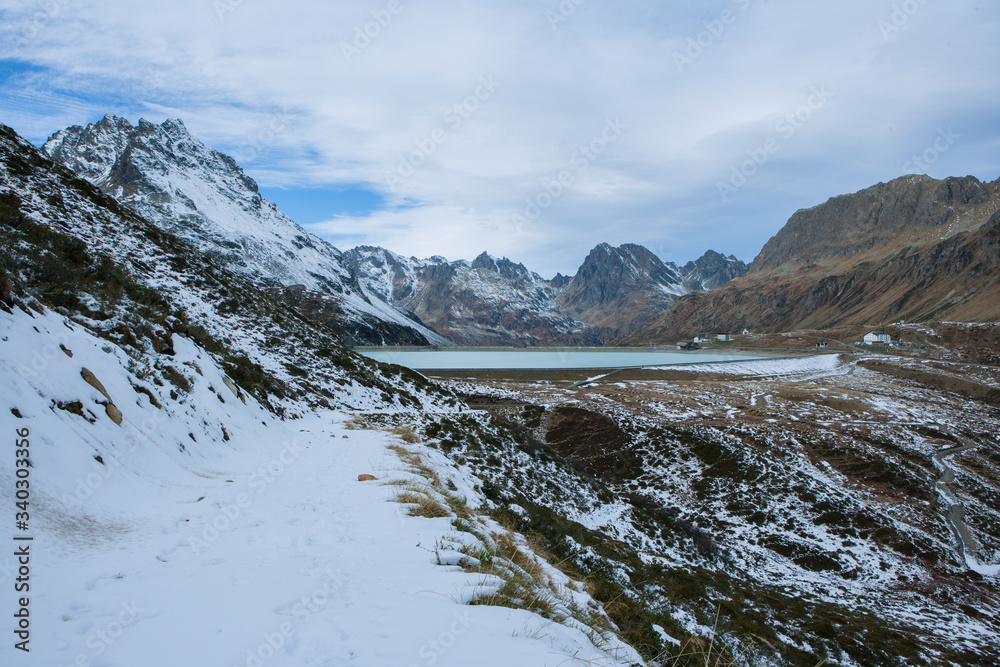 Mountain path in the mountains and snow with a view of the Silvretta dam in Austria