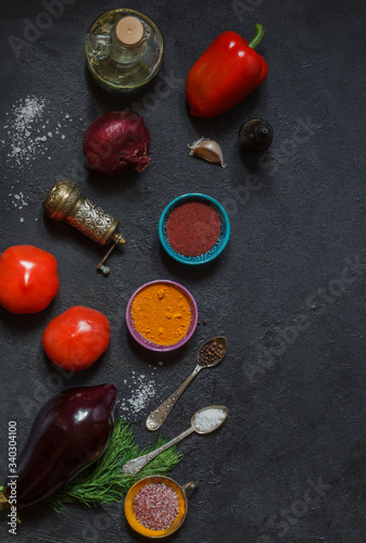 Raw vegetables and bright spices on a black table on top