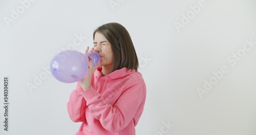 Young woman blowing a pink balloon