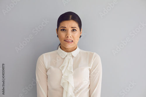 Tableau sur toile Tense young woman looking at camera on gray wall