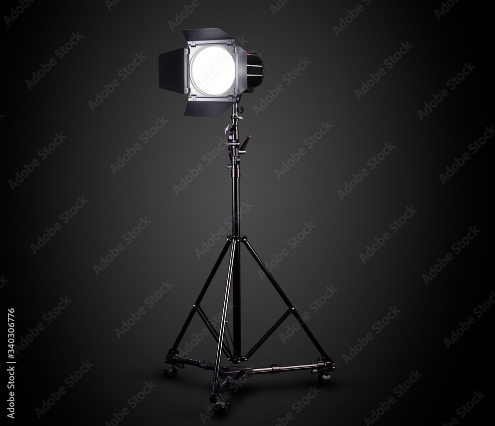 Photography studio flash on a lighting stand isolated on black background.