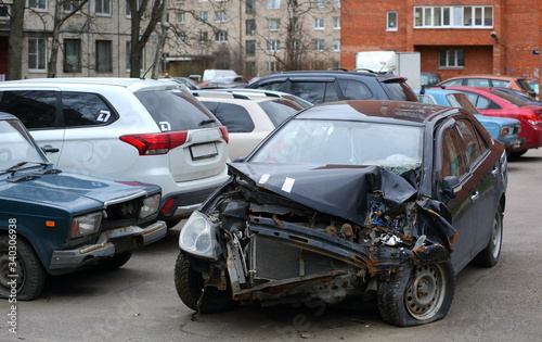 A crashed black passenger car after an accident in the Parking lot of a residential building