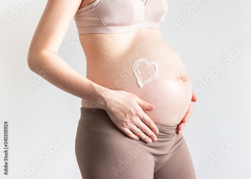 Wallpaper Mural Close up shot of pregnant woman, heart shape stretch mark cream, mother expecting twins over grey background Torontodigital.ca