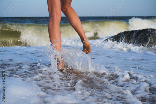 Female legs on the sea beach, footprints in the sand, vacation and travel concept.