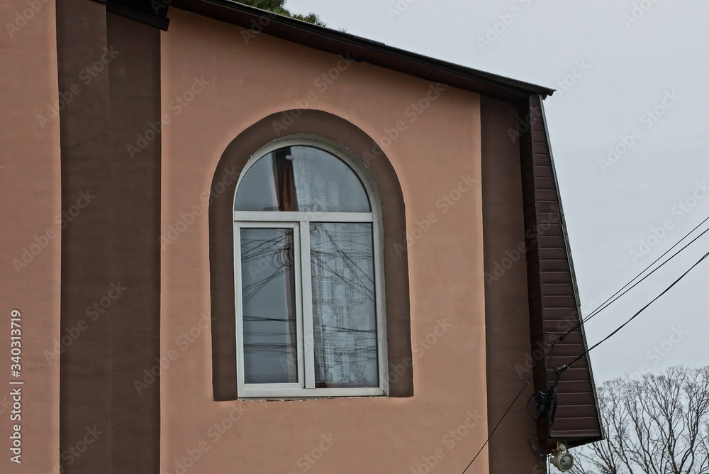 one brown window on the wall of the house with a gray sky one brown window on the wall of the house with a gray sky