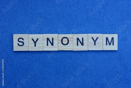 the inscription from the gray word a synonym from small wooden letters lies on a dark paper blue background