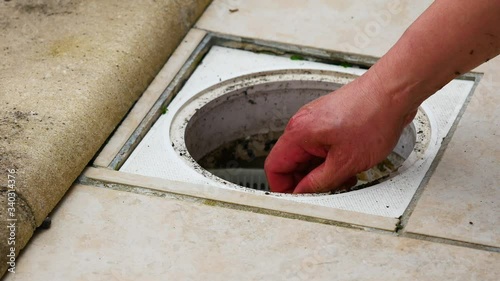 A man removing the swimming pool skimmer basket full of garbage, debris to clean out. Cleaning a very dirty pool after long months of winter.