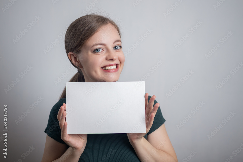 Smiling young Caucasian woman girl holding blank white paper sheet with copy space Smiling young Caucasian woman girl holding blank white paper sheet with copy space