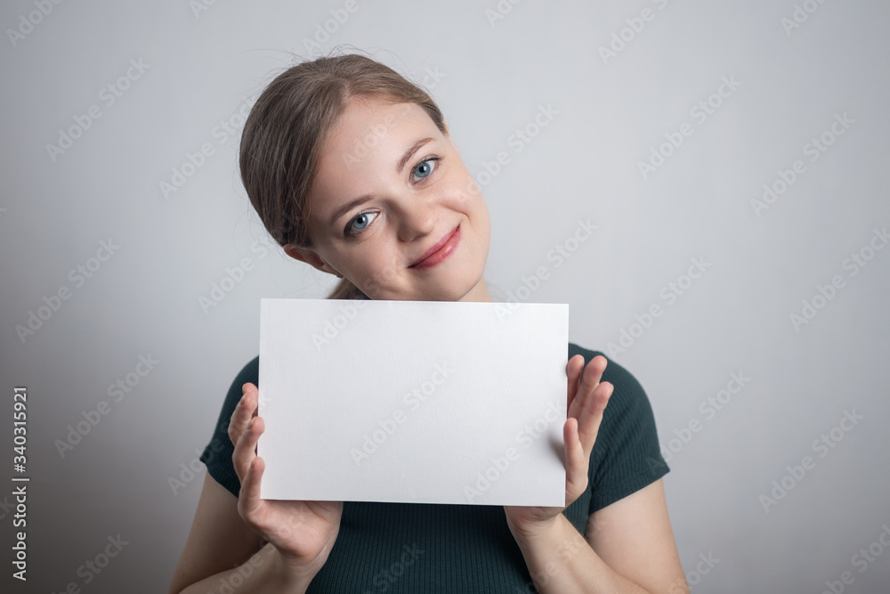 Smiling young Caucasian woman girl holding blank white paper sheet with copy space Smiling young Caucasian woman girl holding blank white paper sheet with copy space
