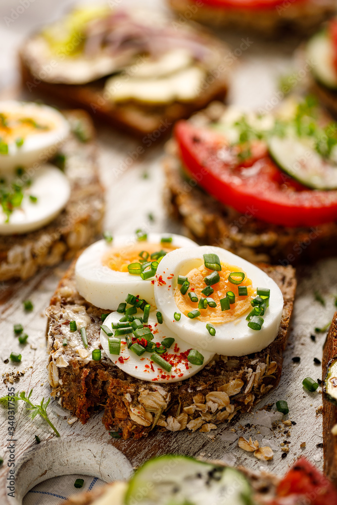 Buckwheat bread sandwich with boiled egg and chives on a wooden board. Close up view
Buckwheat bread sandwich with boiled egg and chives on a wooden board. Close up view