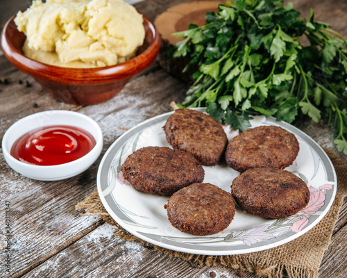 Side view on delicious roasted cutlets on a plate on the wooden table with red sauce, horizontal