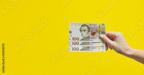 Female hands holding Ukrainian banknotes on yellow background. Banknote of Ukrainian hryvnias