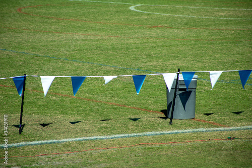 Flag border on the grassy green sports field with a wastebasket