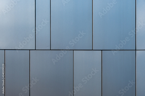 Fotografia Stainless steel facade cladding shining in different grey and blue tones buildin