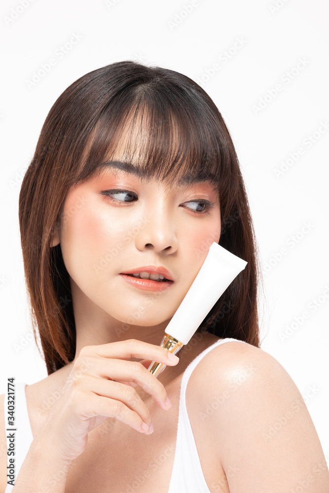 Naklejka premium Beautiful Young Asian Woman Holding luxury white clean tube smile feeling so happy and cheerful with healthy Clean and Fresh skin,isolated on gray background,Beauty Cosmetics spa and treatment Concept