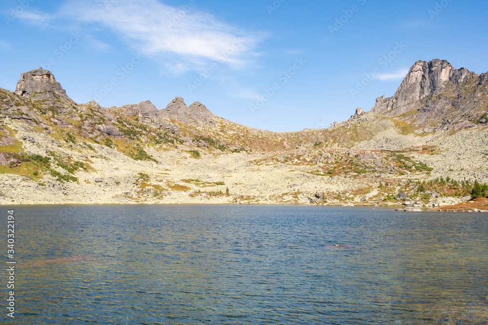 lake under rock ridge, autumn hiking in mountain valley