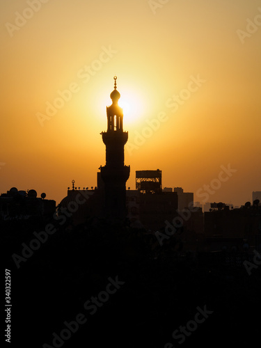 the sun hits the minaret of a mosque as the sun sets in Cairo
