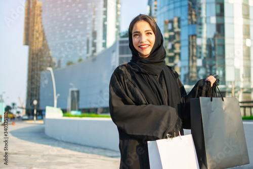 Photography Beautiful Arab woman with shopping bags leaving shopping mall outdoors