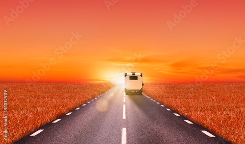 Wohnmobil auf Straße bei Sonnenuntergang zum Horizont