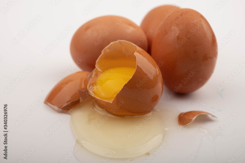 A broken chicken egg and scattered eggs on a white background. Close up. A broken chicken egg and scattered eggs on a white background. Close up.
