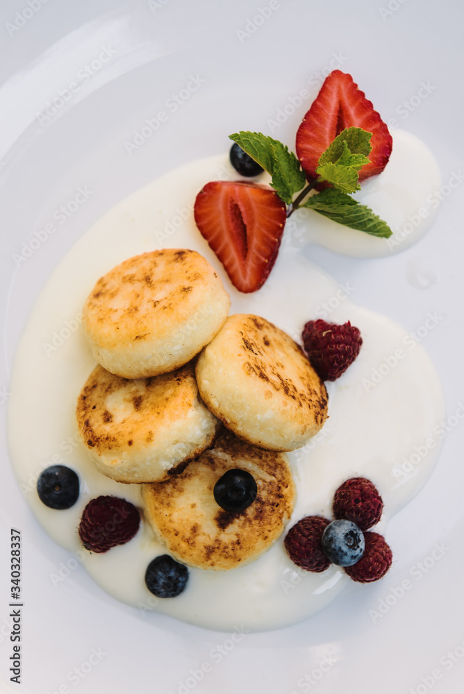 Cheesecakes with berries and sauce close-up on a plate. Cheese pancakes with berries and grape sauce. Cheesecakes with berries and sauce close-up on a plate. Cheese pancakes with berries and grape sauce.
