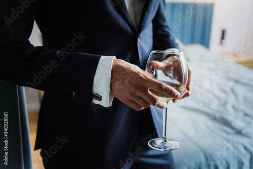 A glass with white wine in the hands of a man close-up.